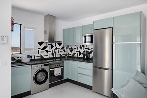 Une cuisine moderne équipée d’appareils électroménagers en acier inoxydable, d’un lave-linge et de meubles de couleur bleu clair.