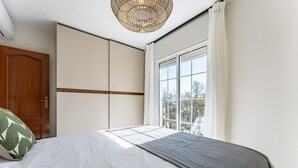 Een slaapkamer met een bed, een raam, een deur en een plafondlamp.