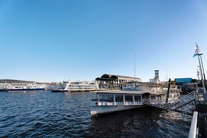 A waterfront dock with a boat, a pier, and a building with a tower.