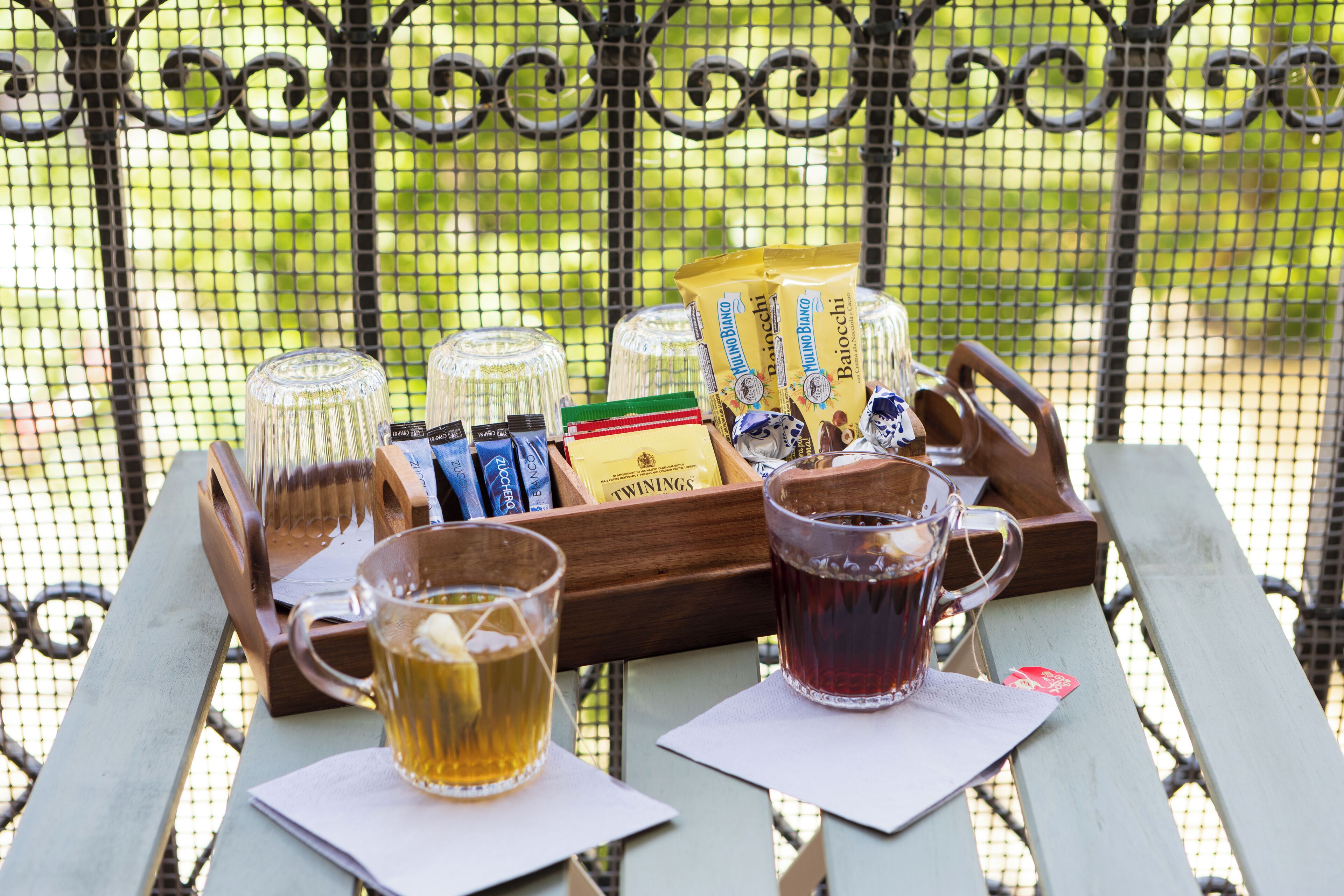 Een picknickopstelling met een dienblad vol lekkernijen, een waterfles en twee theeglazen op een houten tafel.