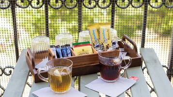 Een picknickopstelling met een dienblad vol lekkernijen, een waterfles en twee theeglazen op een houten tafel.