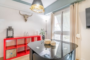 A room with a glass-top table, red shelving unit, a wall-mounted bull skull, and a ceiling light fixture.