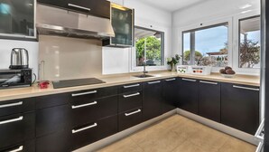 Una cocina moderna con armarios negros, electrodomésticos de acero inoxidable y un amplio ventanal con vistas al exterior.