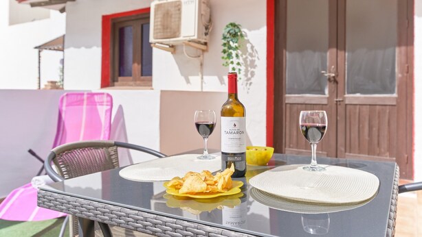 Une table avec une bouteille de vin, deux verres et un bol de chips.