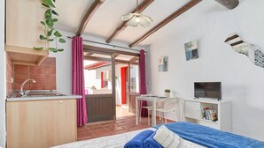 Une chambre d’hôtel de taille réduite, comprenant un lit, une petite kitchenette, un bureau et un téléviseur.