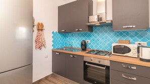 Una cocina moderna con gabinetes grises, un revoque de azulejos azules, una estufa a gas, un microondas y un tostador.