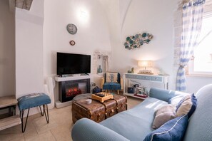 A living room with a television, fireplace, sofa, and a blue chair.