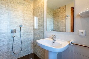 A modern bathroom with a shower, sink, and mirror.