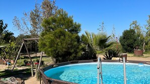 A clear blue sky, a swimming pool, and surrounding trees.