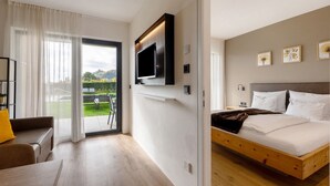 Ett modernt hotellrum med en säng, en tv som är monterad på väggen, en soffa och utsikt över omgivningarna.