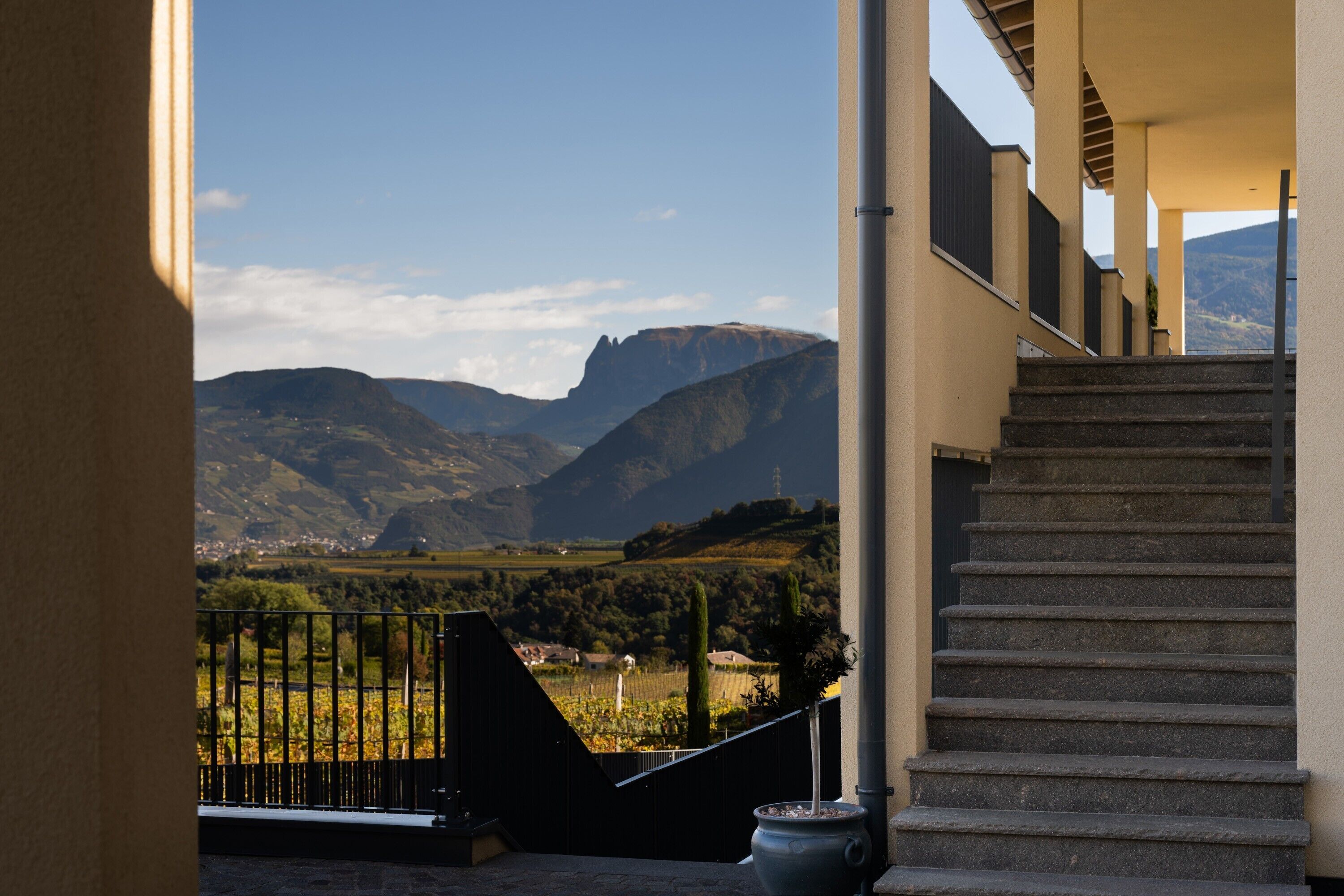 A staircase leading to a balcony overlooking a mountainous landscape with a clear sky.