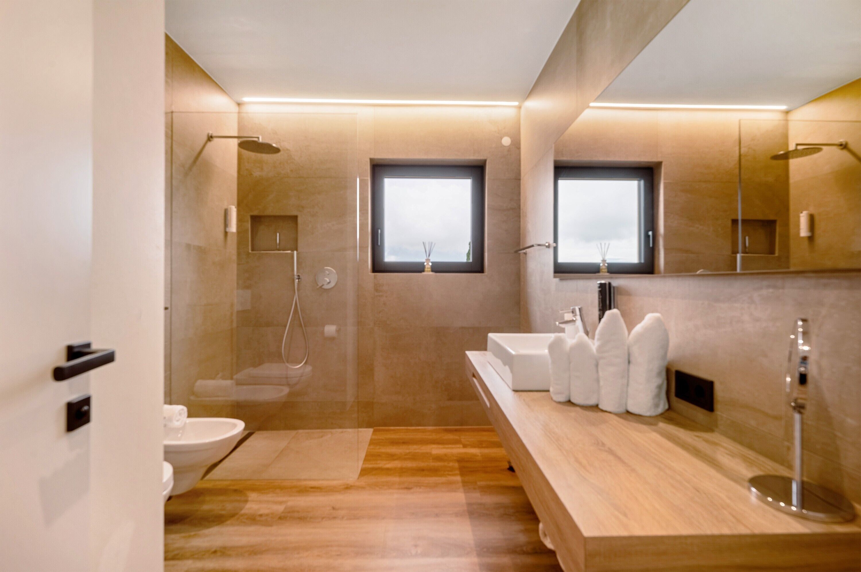 Ein modernes Badezimmer mit Dusche, Toilette und Waschbecken, ausgestattet mit einem Holz-Waschtisch und einem großen Spiegel.
