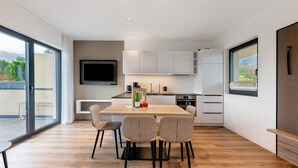 Eine moderne Küche mit Essbereich, großen Fenstern und einem Flachbildfernseher.