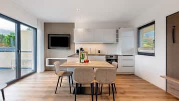 Een moderne keuken met een eethoek, grote ramen en een flatscreen televisie.