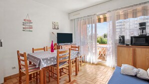 Ein Essbereich mit Tisch und Stühlen, einem Fernseher, einer Kaffeemaschine und Blick durch ein Fenster.