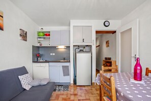 Un espacio habitable pequeño con kitchenette, comedor y sofá.
