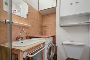 Une salle de bain équipée d’un lavabo, d’un miroir, de toilettes et d’un lave-linge.