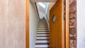 Eine Treppe mit Holzboden und Geländer, die zu einer Zwischenebene mit einer Tür führt.