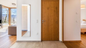 Een modern interieur met een houten deur, een grote spiegel en uitzicht door een raam.