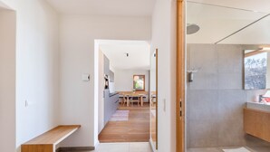 Een modern interieur met een houten bank, een keukenhoek en een badkamer met douche.