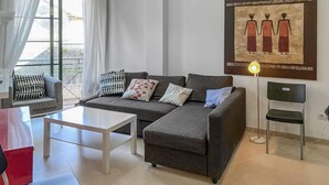 A modern living room with a grey sofa, a white coffee table, and a black chair. There is a painting on the wall and a floor lamp. - Amazing home in Ortigueira with WiFi (Ortigueira)