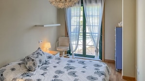A bedroom with a bed, a chair, a lamp, a wardrobe, and a window with curtains. - Amazing home in Ortigueira with WiFi (Ortigueira)