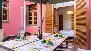 A dining table set for two with a floral tablecloth, a bottle of wine, and a candle. - Holiday Home 'Dellarose Max' with Private Terrace, Wi-Fi and Air Conditioning (Porto)
