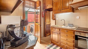 Una cocina con armarios de madera, una cafetera, una lavadora y un lavamanos.