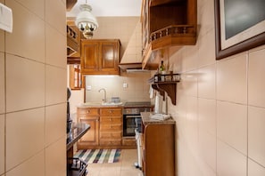 Uma cozinha estreita com armários de madeira, forno embutido e painel de azulejos.