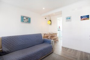 A living room with a sofa, a dining table, and a kitchen area in the background. - Lovely vacation home Baleal atlantic 6 (Ferrel)