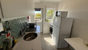 Una cocina moderna con un lavaplatos de acero inoxidable, lavadora integrada y un microondas en la encimera.