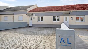 Un bâtiment doté d’un toit en tuiles, d’une cour pavée et d’une enseigne indiquant « AL (hébergement local) ».