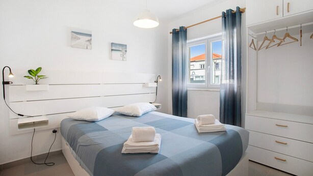 Une chambre moderne avec un lit, des tables de chevet, une armoire et une fenêtre avec des rideaux.