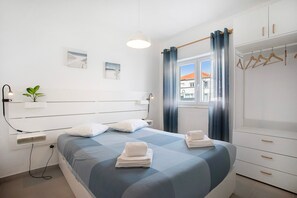 A modern bedroom with a bed, bedside tables, a wardrobe, and a window with curtains.