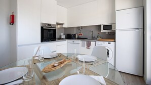 Eine moderne Küche mit weißen Schränken, einem Geschirrspüler, einer Mikrowelle und einem Kühlschrank.