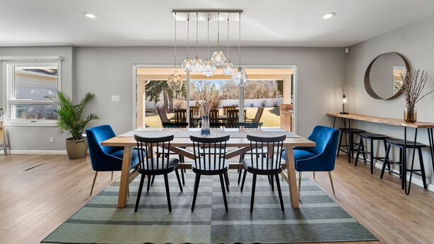 Un espace repas moderne avec une table en bois, des chaises bleues et un luminaire suspendu.