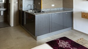 A modern kitchen with grey cabinets, a granite countertop, and a built-in stove. - Immeuble Gazbar (Gabes)