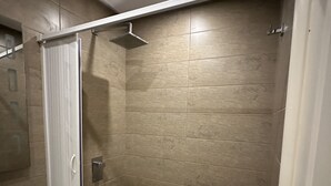 A modern bathroom with a shower, a white sink, and a tiled floor. - Immeuble Gazbar (Gabes)