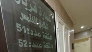 A hallway with a glass display case listing room numbers 51 to 54. - Immeuble Gazbar (Gabes)
