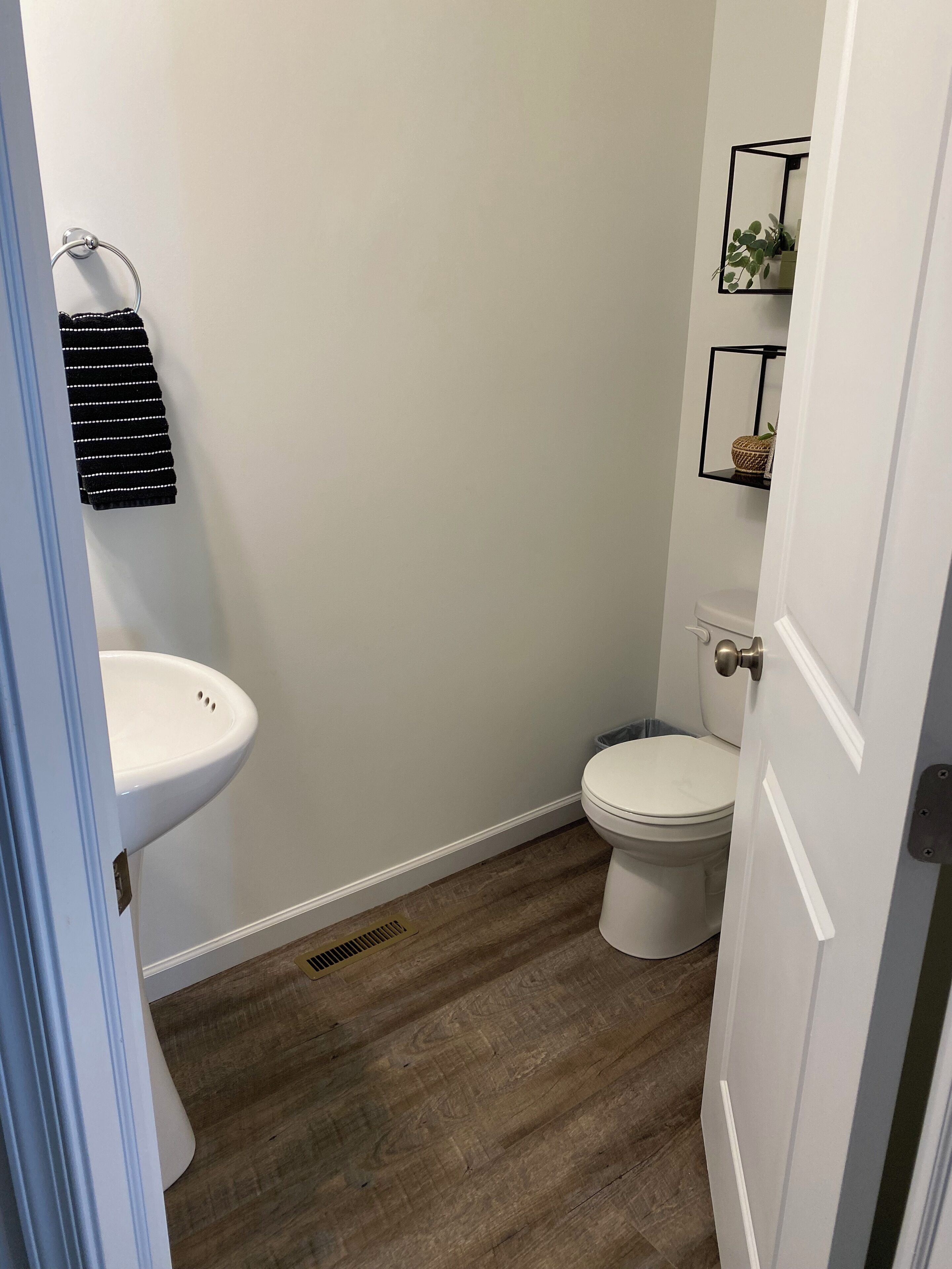 Ein Badezimmer mit Waschbecken, Toilette und einem kleinen Regal mit einer Pflanze.