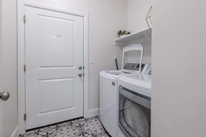 A laundry room with a white door, a washing machine, and an oven.