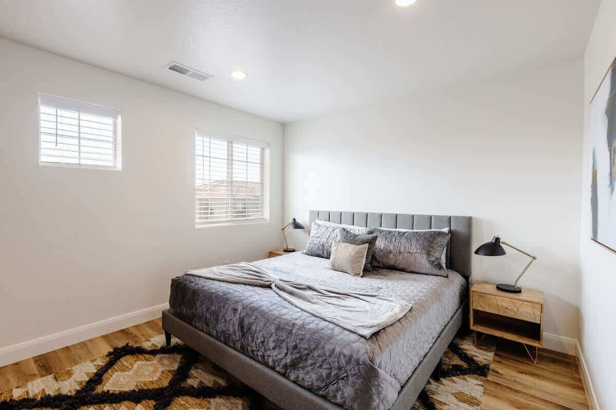 Un dormitorio con cama, mesitas de noche, ventana y cabecera.