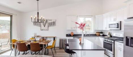 Una cocina moderna con armarios blancos, electrodomésticos de acero inoxidable y una isla central.