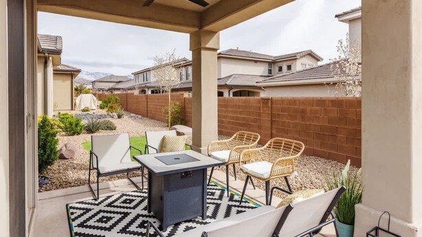 A covered patio with a ceiling fan, outdoor seating, and a view of neighboring houses.