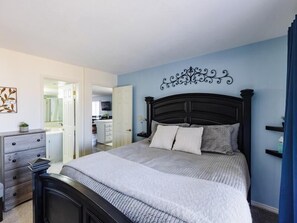 Une chambre à coucher comprenant un lit, une commode et un élément décoratif mural.