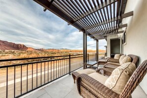 A balcony with wicker furniture and a view of a desert landscape.
