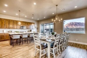 A spacious kitchen with wooden cabinets, a central island, and a dining area with white chairs.