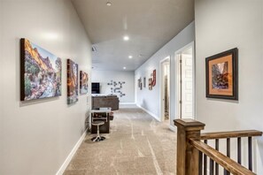 A hallway with artwork on the walls, a reception desk, and a staircase.