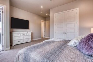 A bedroom with a bed, a dresser, a television, and a closet.