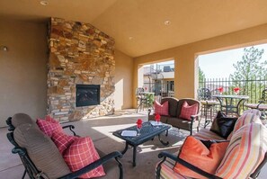 An outdoor patio with stone fireplace, seating, and a view of the neighborhood.
